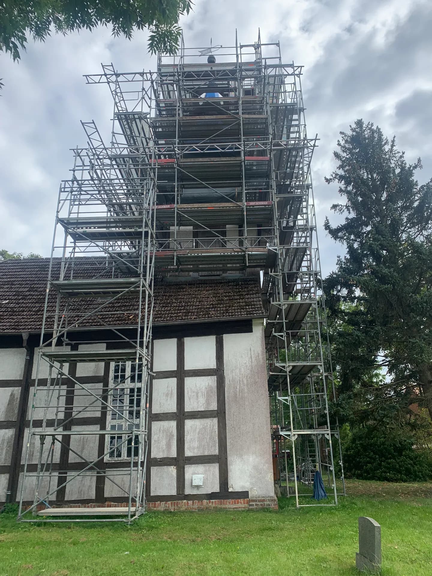 Turmgerüst mit Seitenschutz über dem Dach der Fachwerkkirche Braunsberg, Arbeitsebenen entlang der Traufe