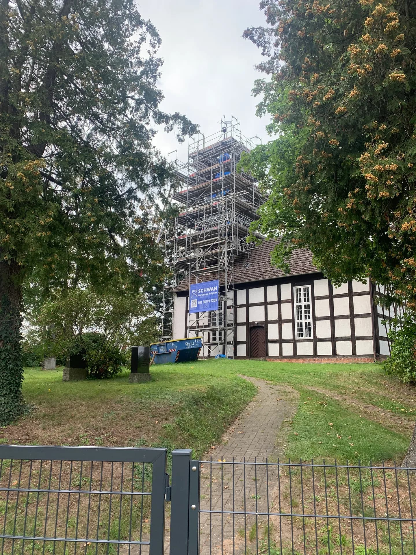 Blick über den Kirchhof auf den eingerüsteten Turm der Kirche Braunsberg