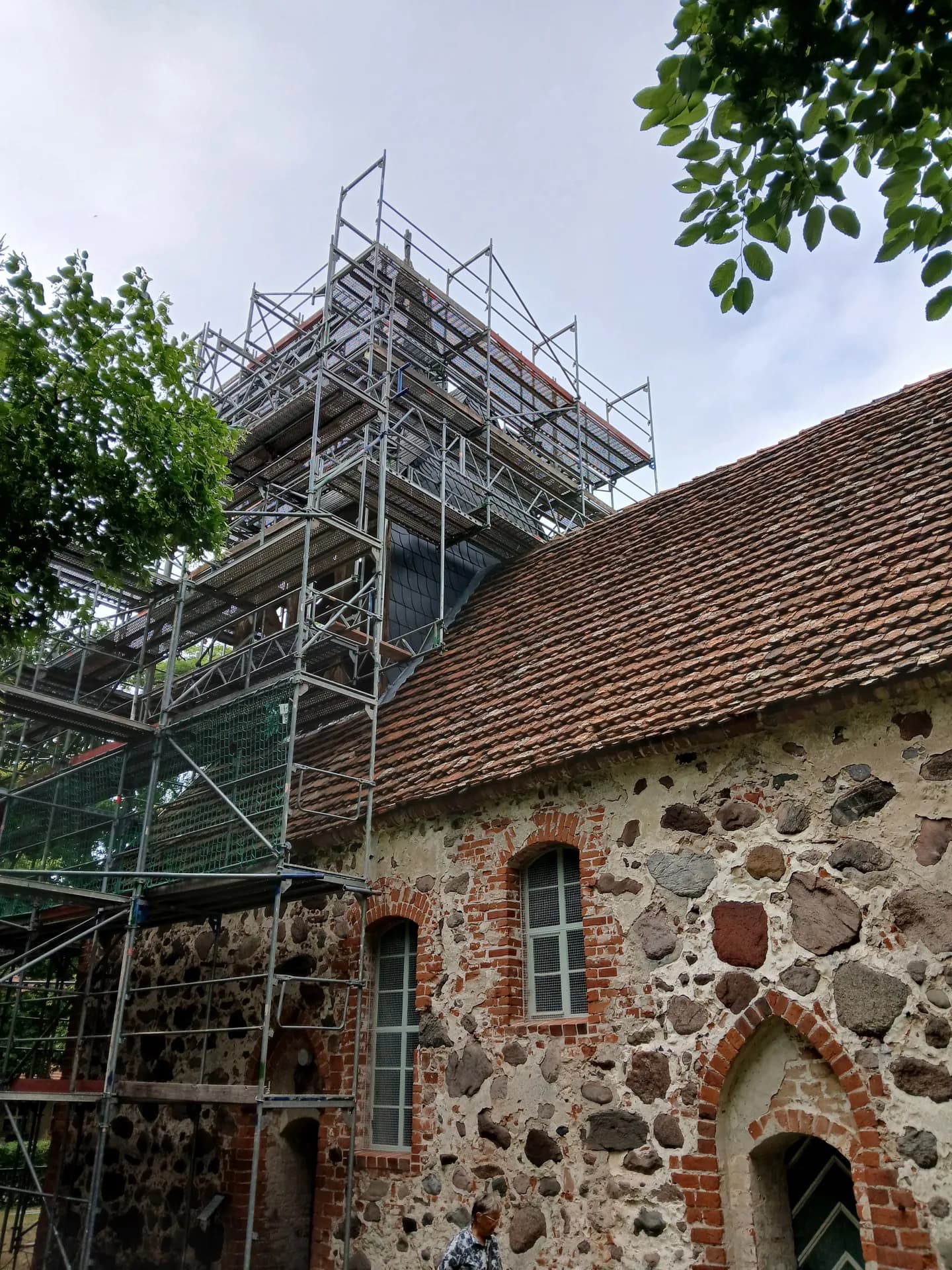 Blick am Turm hinauf zum Gerüst mit auskragenden Ebenen und Schutznetz, Dorfkirche Gnewikow
